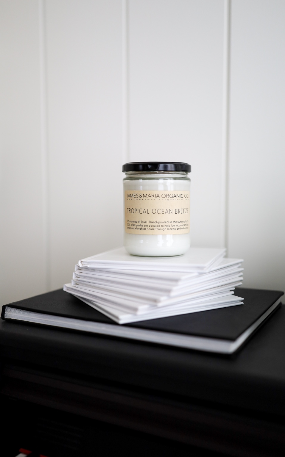 Candle styled on a stack of neutral books in soft natural light